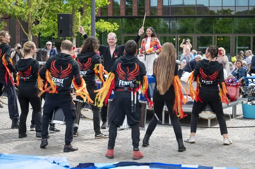 Fenix Drums op een plein bij een theater in Den Bosch, met publiek op de achtergrond